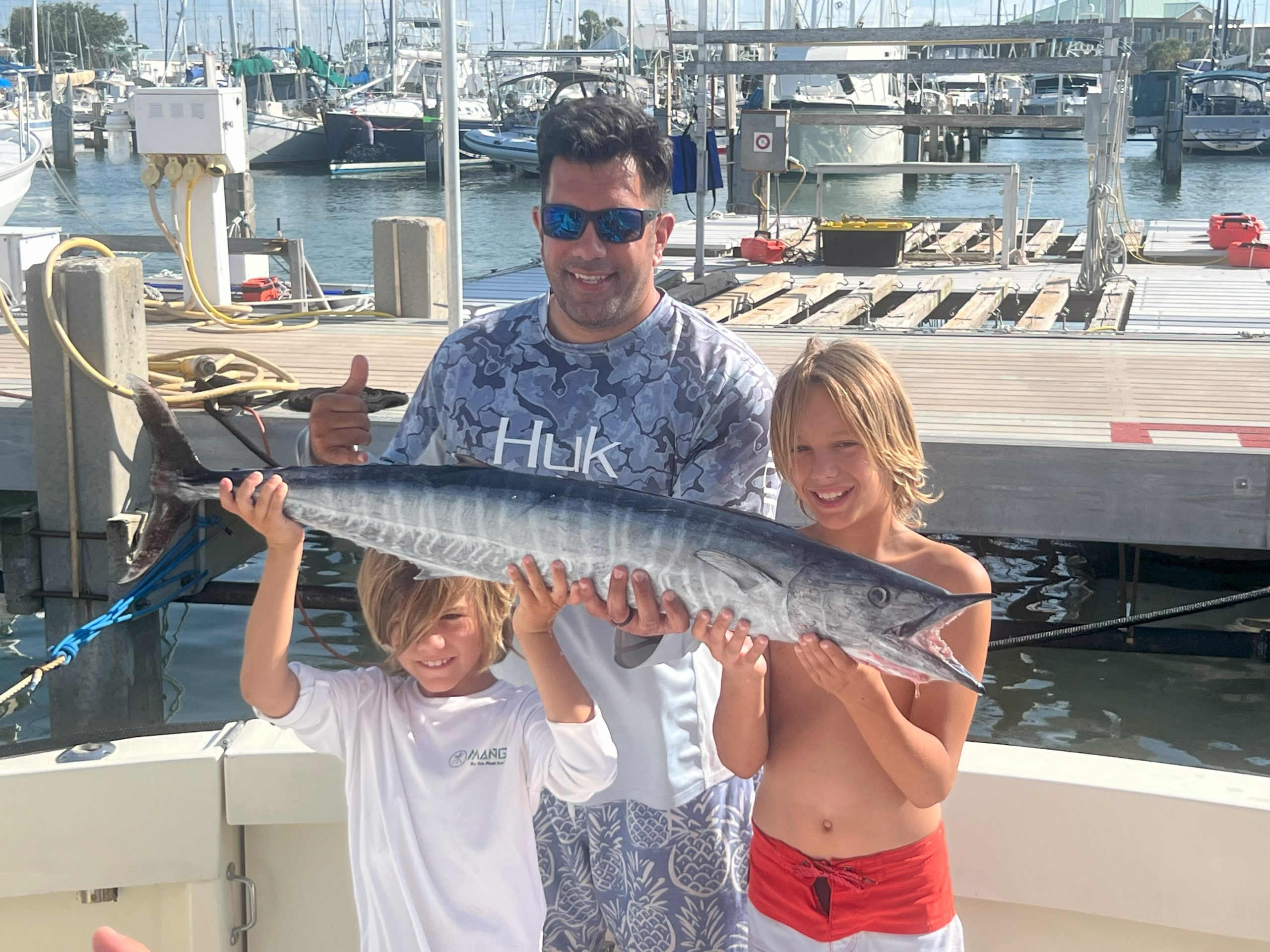 Father and two sons holding a wahoo they caught in the Gulf Stream off Port Canaveral